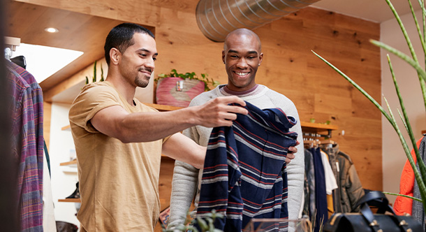 two men shopping for clothing in a stylish store examining a striped shirt together in a fashionable setting