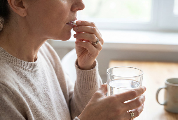 woman taking medicine with glass of water for health and wellness goals